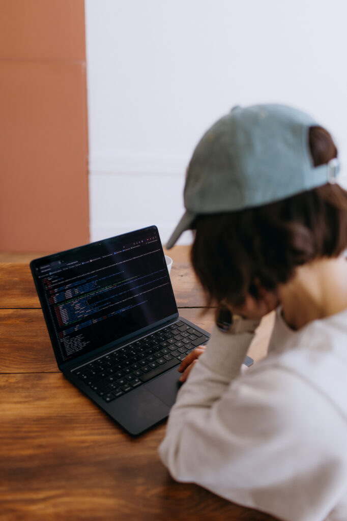 Femme avec une casquette en train de coder sur un ordinateur